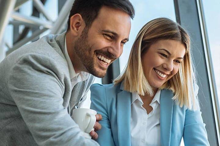 Two professionals smiling and looking at something together.